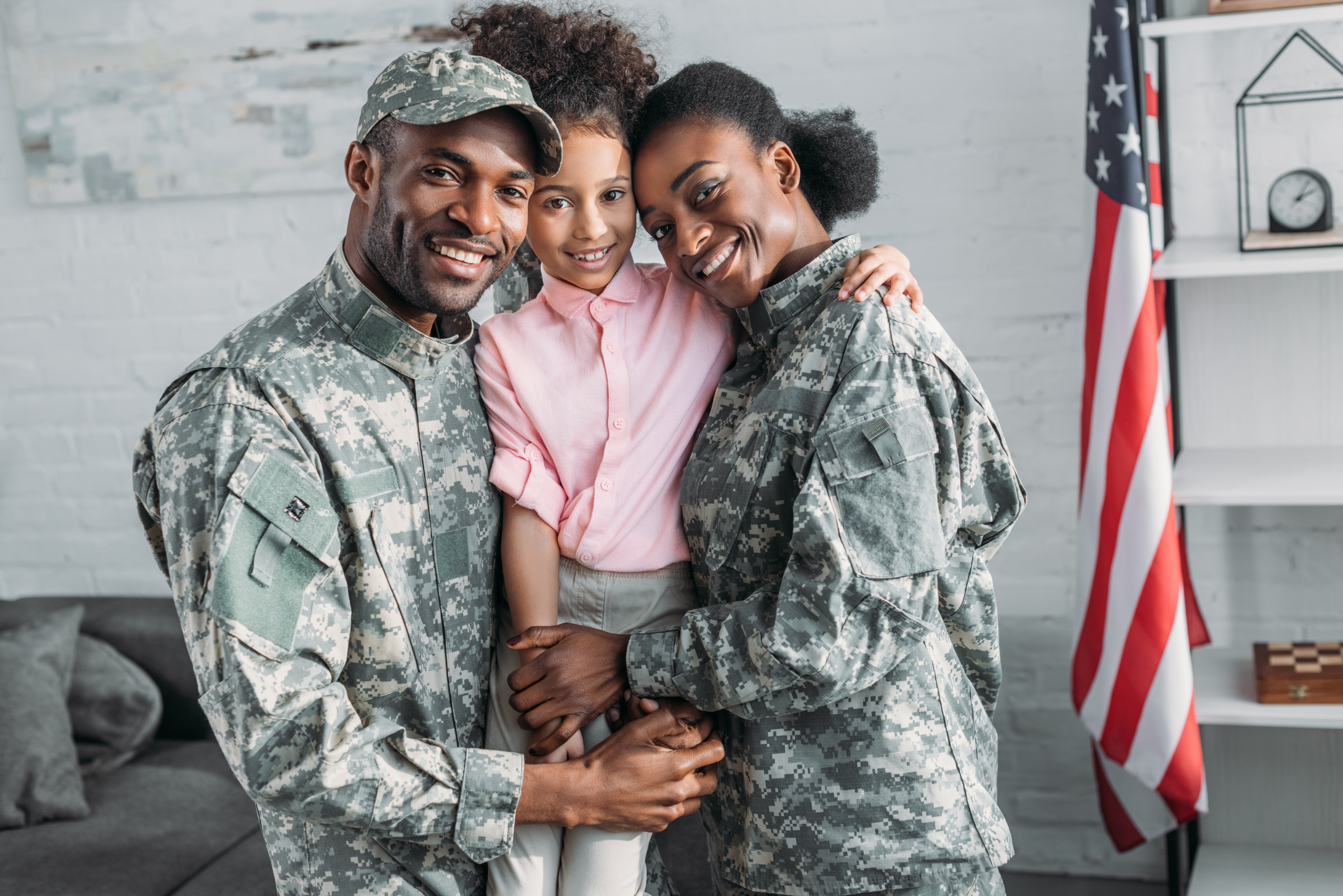 African American military family. Mom and dad in fatigues holding their adolescent daughter and smiling.